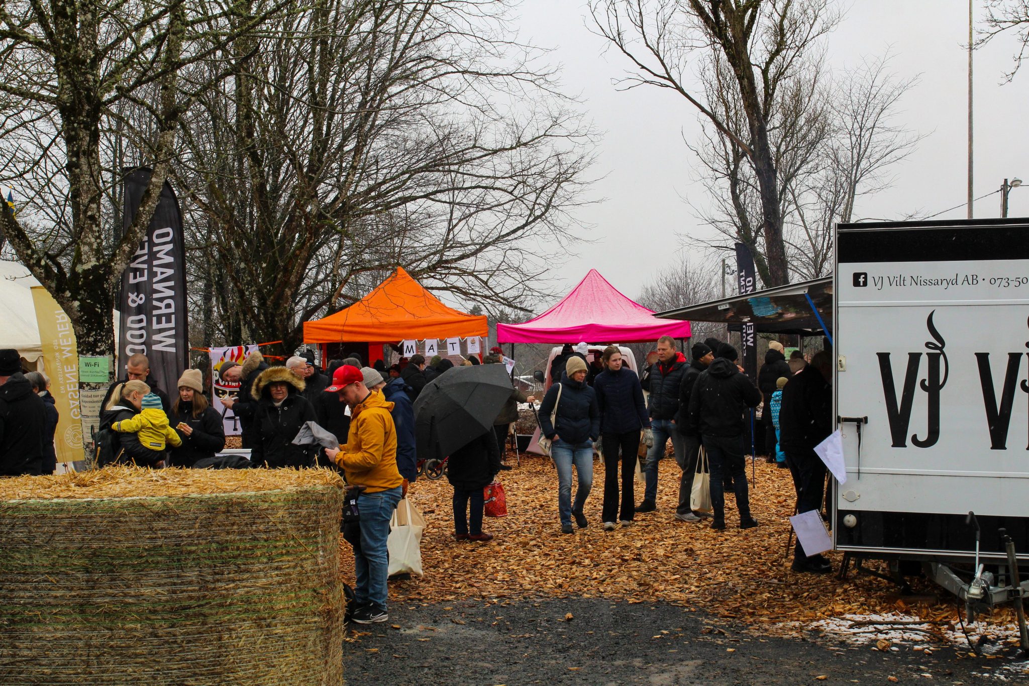 Personer utomhus och två tält i bakgrunden