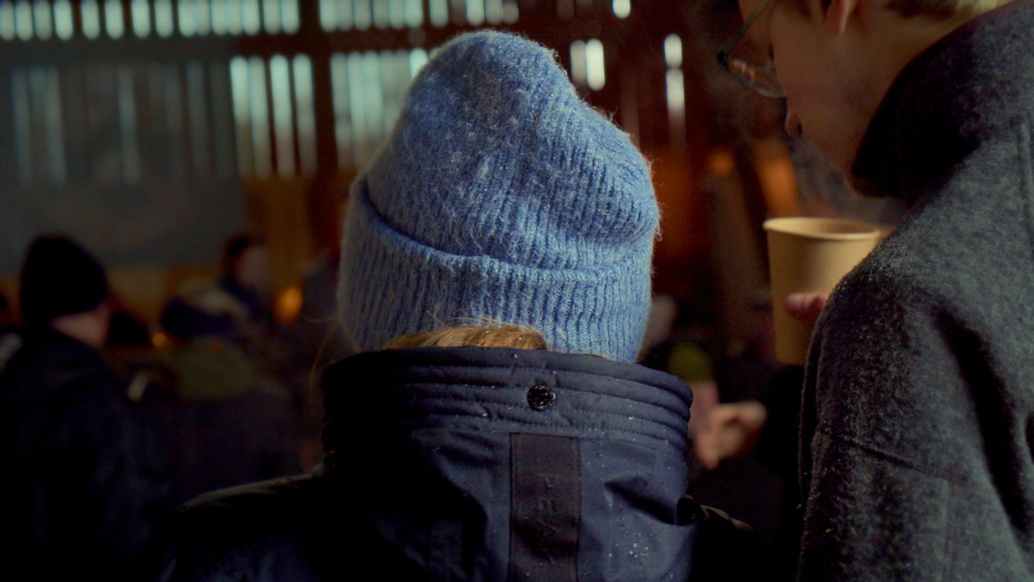 En person som står inomhus och har en ljusblå mössa på sig