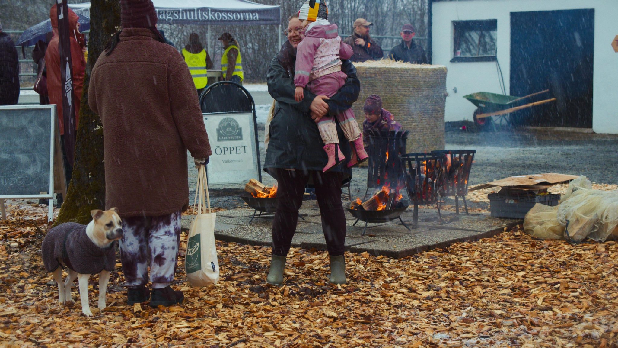En kvinna som håller i ett barn med rosa kläder utomhus