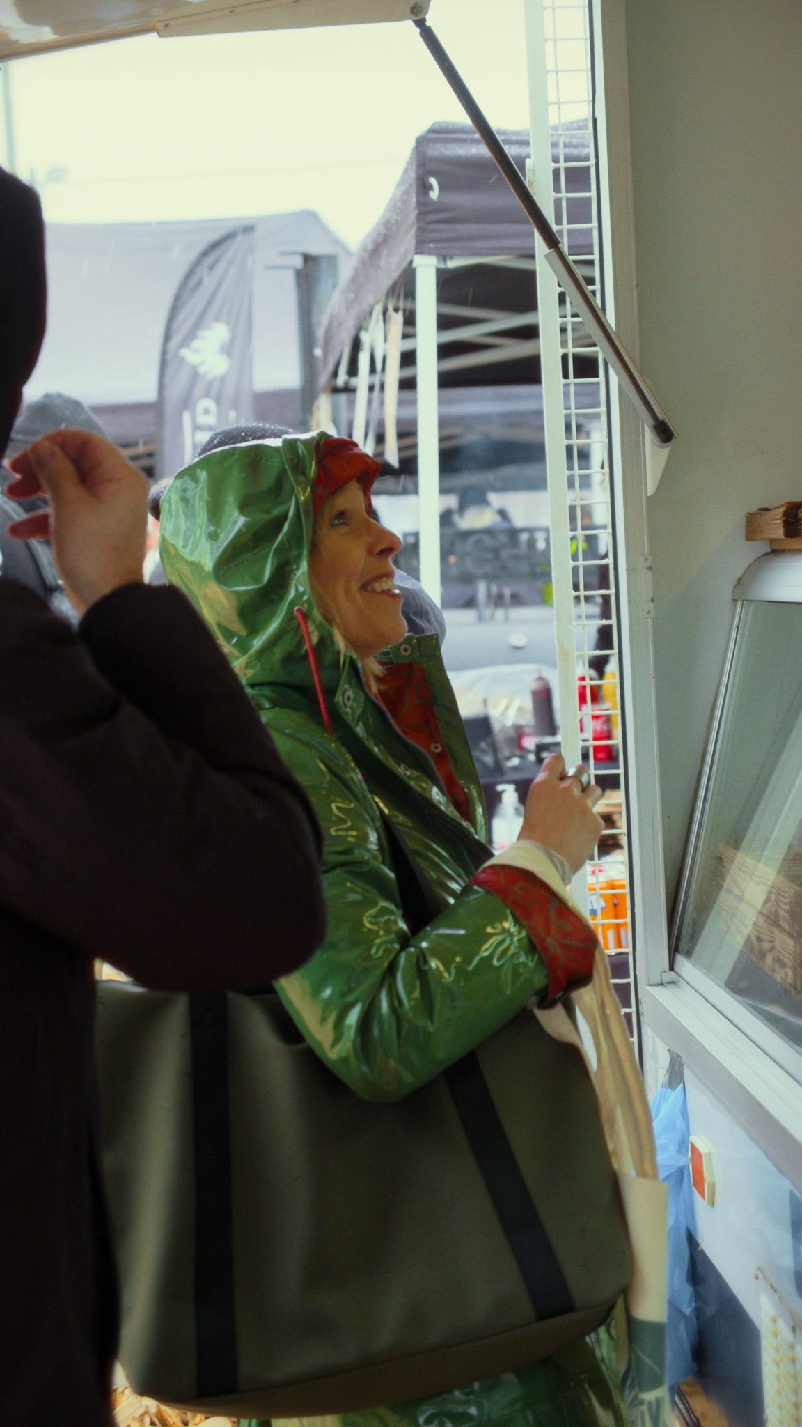 En kvinna som ler med en grön regnjacka